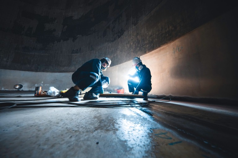 Male worker inspection vacuum test bottom plate tank petrochemical steel weld leak shutterstock_2578329079